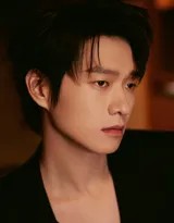 魏大勋正装站立，目光深邃望向远方，黑色西装与简洁背景衬托出其沉静而专注的侧脸