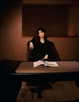 魏大勋在活动背景板前签名留影，身姿挺拔姿态从容，展现自信十足的公众人物风范