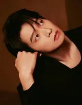 灯光下魏大勋西装面料的质感清晰可见，他微微低头浅笑，氛围温暖而迷人