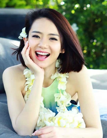 戚薇倚靠树干闭目感受微风，绿色裙衫与自然背景完美融合