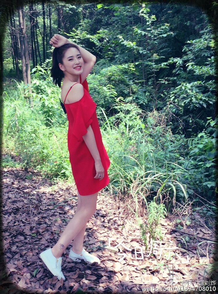 刘烨身着米色风衣倚靠街边栏杆，微风吹动长发，丝袜美腿在阳光下勾勒出优雅线条