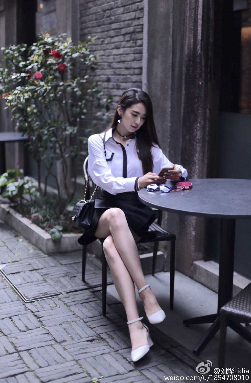 阳光透过树叶洒在刘烨身上，她低头浅笑，丝袜包裹下的双腿并拢微侧，尽显温婉气质