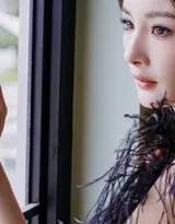 杨幂立于门廊光影交汇处，黑色羽毛礼服在柔和光线下呈现丰富质感，眼神深邃故事感十足