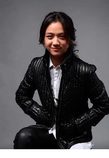 汤唯倚靠沙发抱膝而坐，眼神温柔望向镜头，充满居家般的宁静与惬意