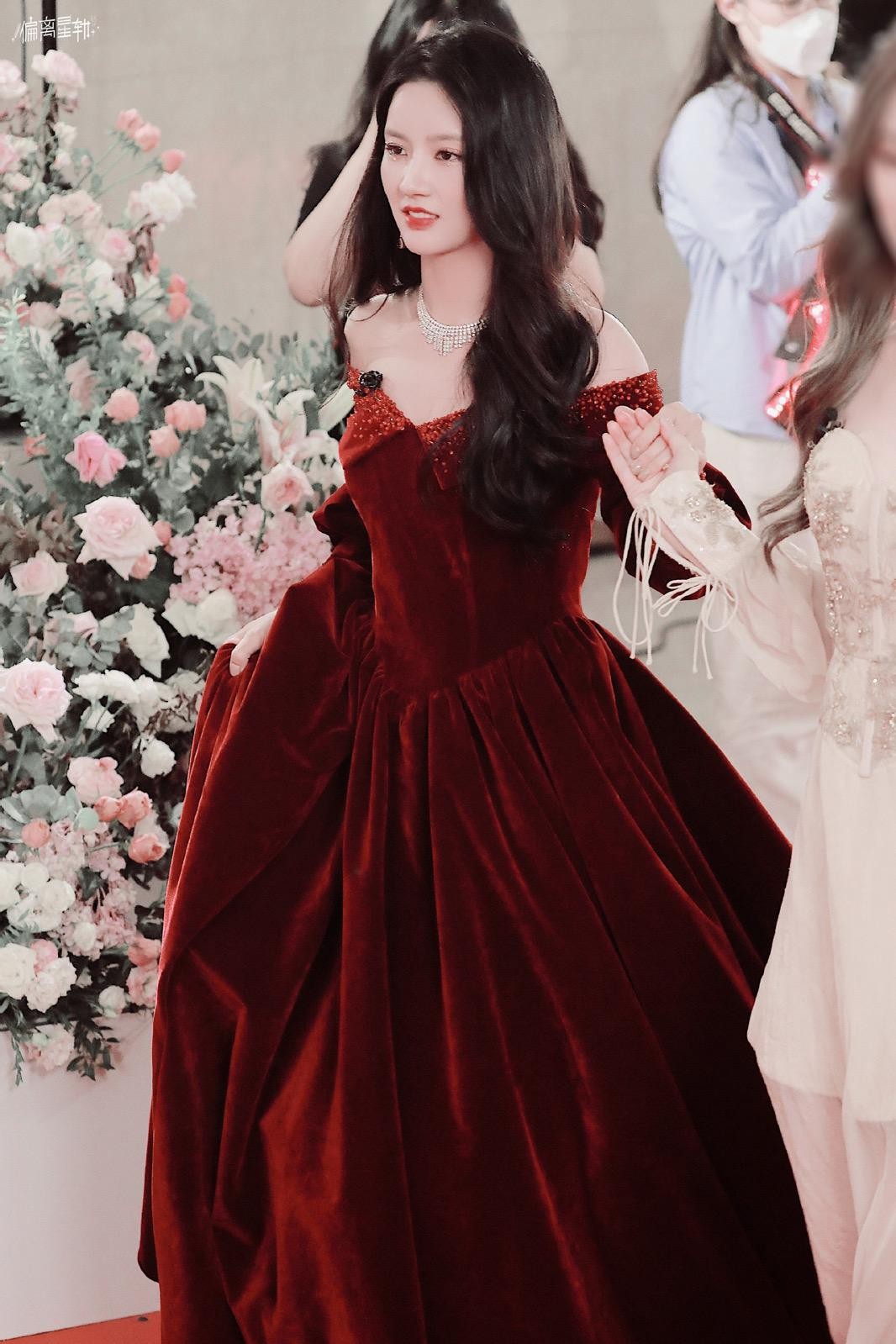 刘些宁轻倚廊柱，白色羽毛礼服衬托出脱俗气质，仿佛不染尘埃的月光仙子