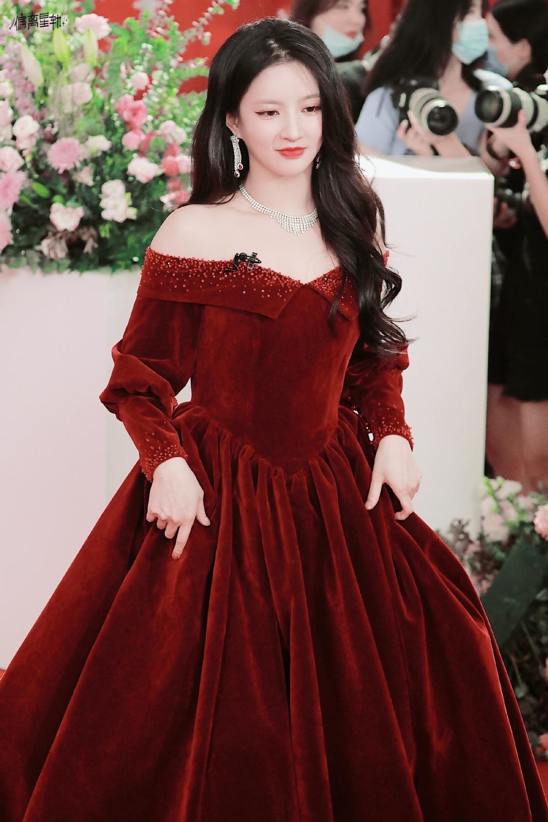 刘些宁置身于古典窗棂前，一袭红裙似火，与背景的深沉形成强烈对比，宛如一幅浓墨重彩的油画